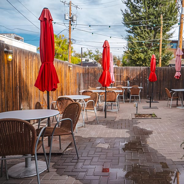 Outdoor patio at Swing Thai Tennyson with red umbrellas, wicker chairs, and string lights.