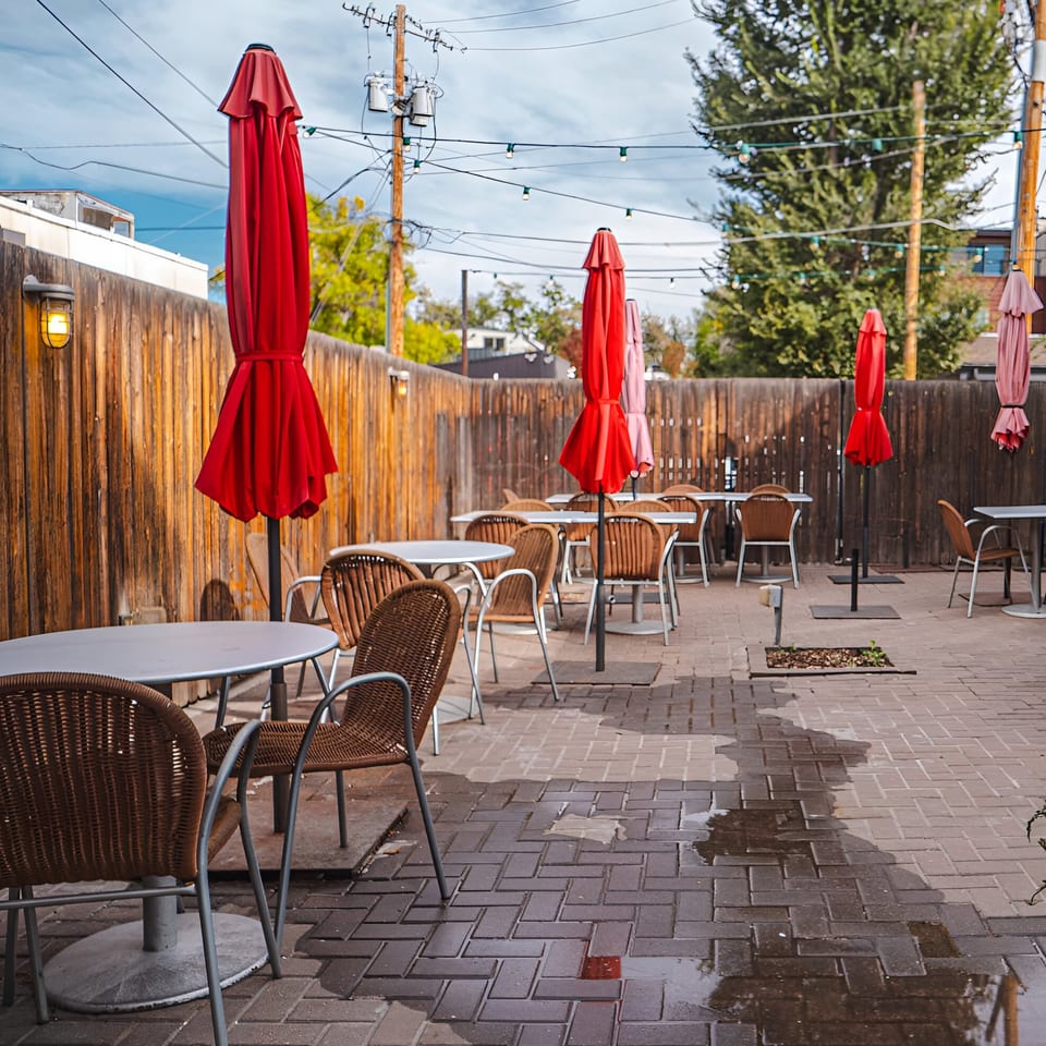 Outdoor patio at Swing Thai Tennyson with red umbrellas, wicker chairs, and string lights.