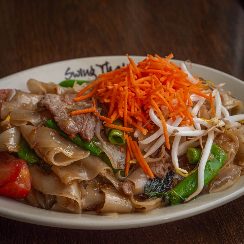 Close-up of Swing Thai Tennyson's Pad See Ew with beef, wide noodles, and fresh vegetables.