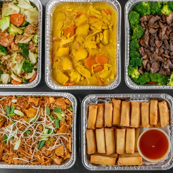 Five foil containers of Thai food, including curry, stir-fry, noodles, and spring rolls with sauce.
