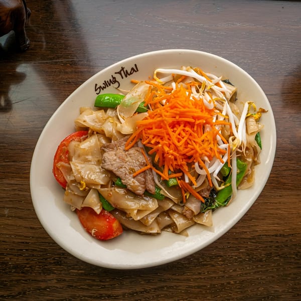 A plate of Swing Thai noodles with beef, tomatoes, snow peas, shredded carrots, and bean sprouts.